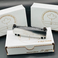Three file guide boxes with one having a file guide on top.  A file guide are used mainly for grinding the ricasso and hidden tang shoulders for custom knife making.