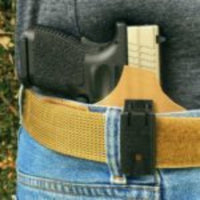 Ulticlip XL  is a black device attached to a tan belt on a man's body. 