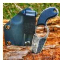 Ulticlip 2.2 on a blue knife sheath on a log beside a dagger. 